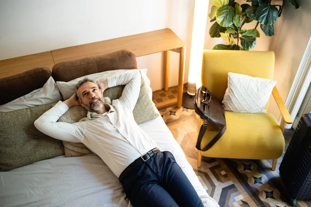 Man relaxing on a bed while comparing recliner and adjustable bed comfort.