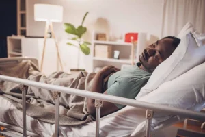 Man resting comfortably in an adjustable bed with raised side rails.