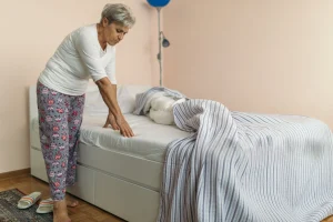 Senior woman adjusting bedding to help prevent bed sores.